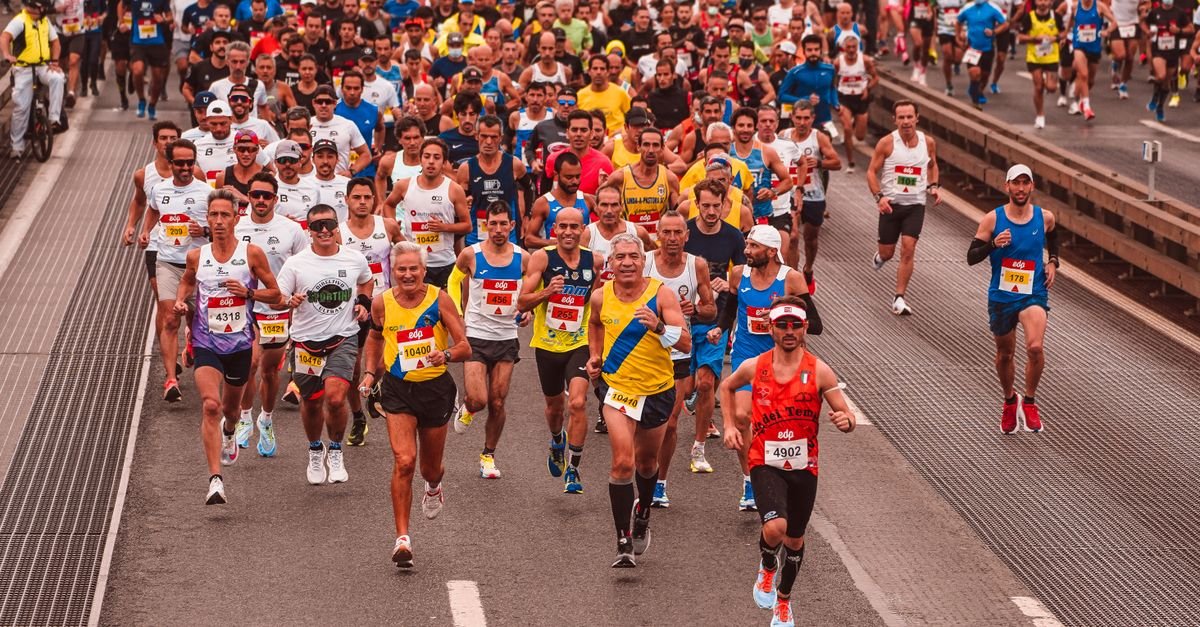 Large group of diverse athletes running a marathon outdoors during the day.