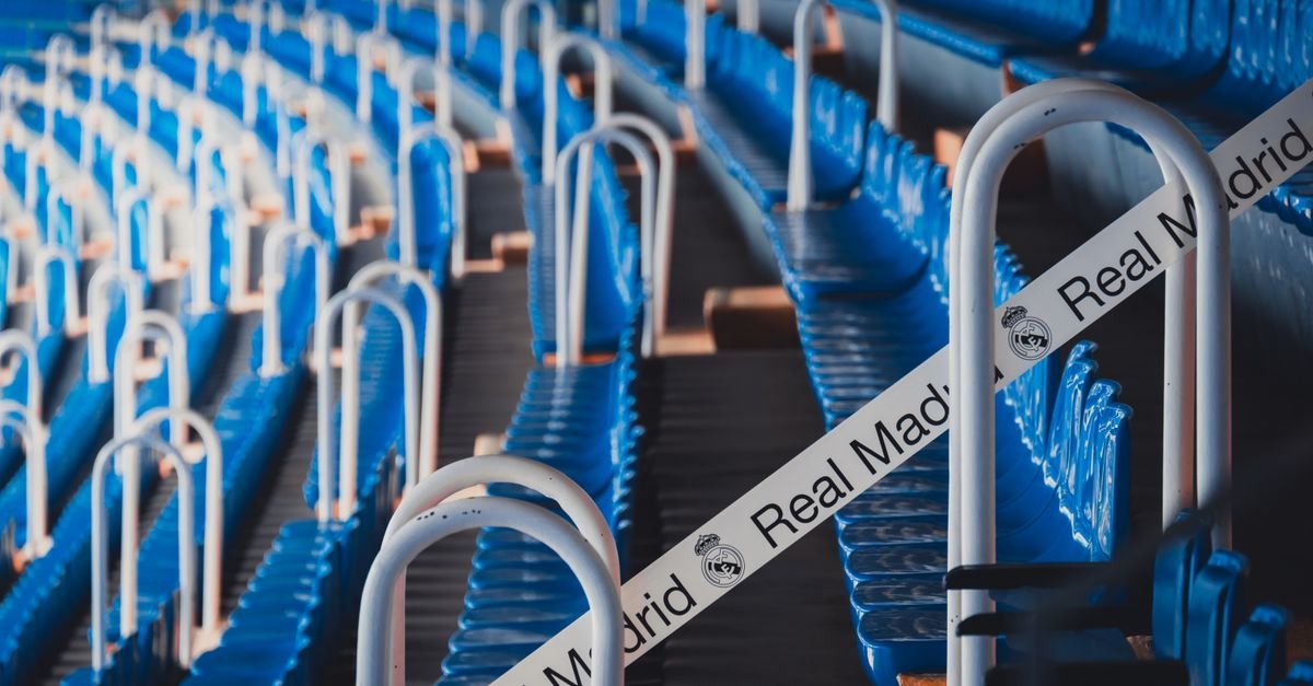Rows of blue stadium seats in Madrid's iconic Bernabéu Stadium, featuring Real Madrid branding.