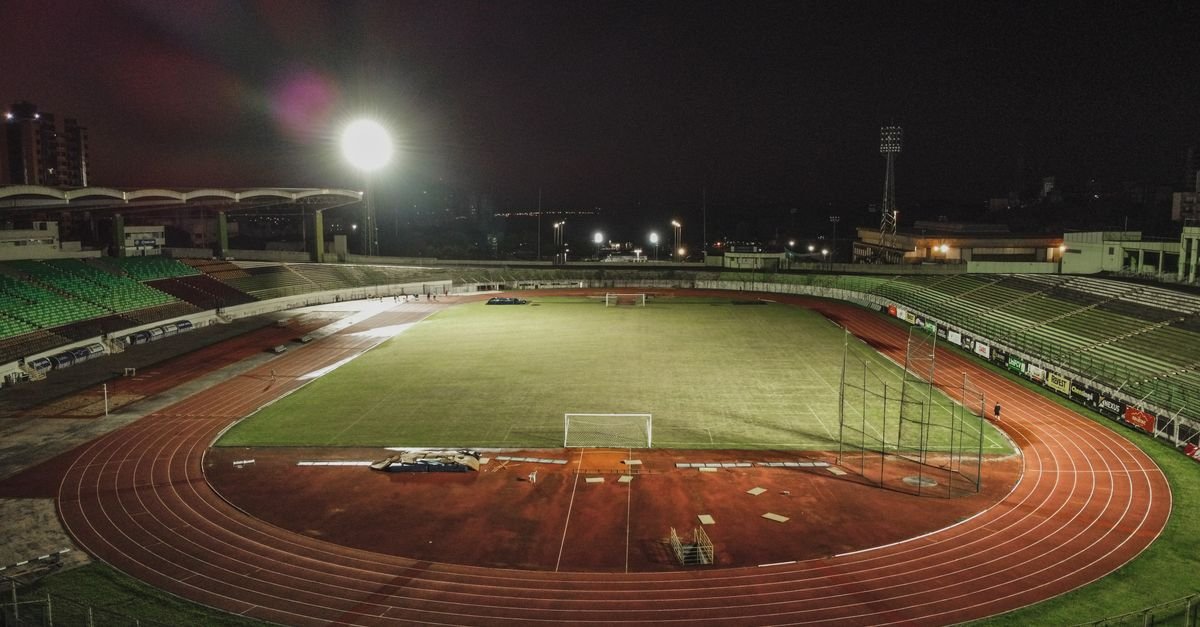 A captivating nighttime aerial view of Estádio Willie Davids in Brazil, showcasing its illuminated field and track.