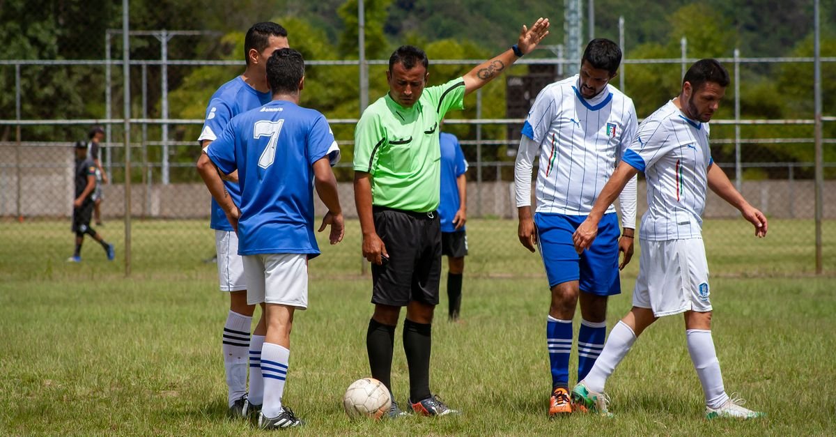 Soccer players and referee on a green field in Venezuela, mid-game action.