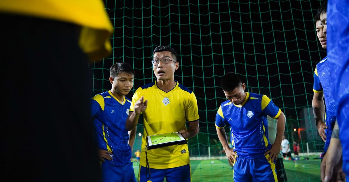 Soccer coach giving strategy talk to players on a night field.