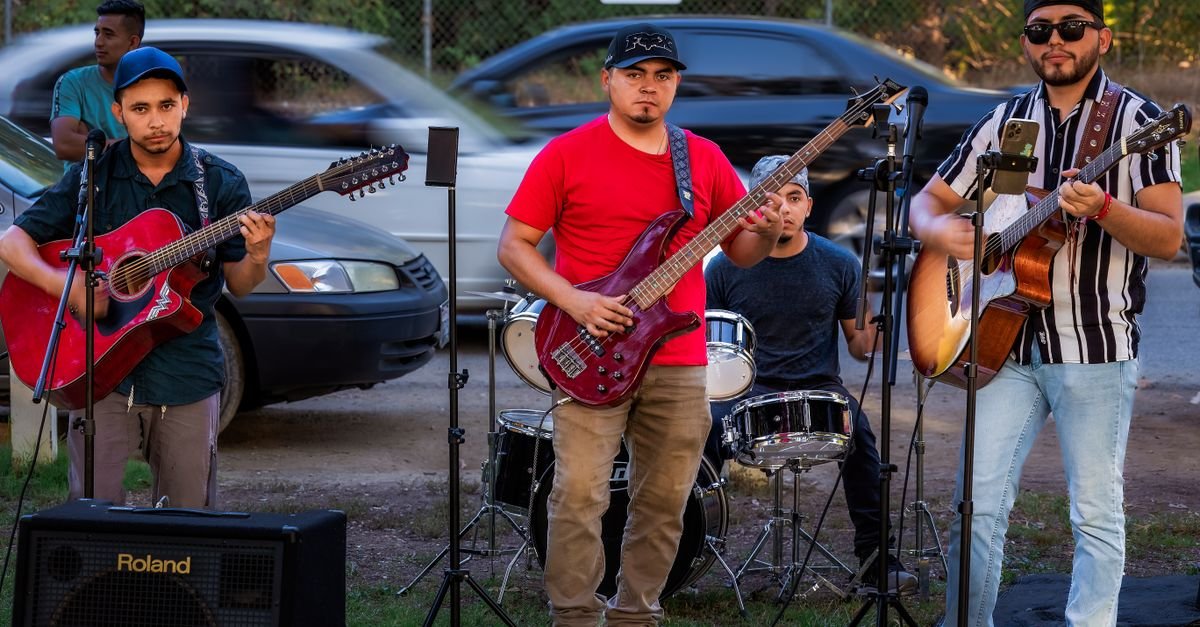 A group of musicians performing live on the roadside with guitars and drums, creating a vibrant street ambiance.