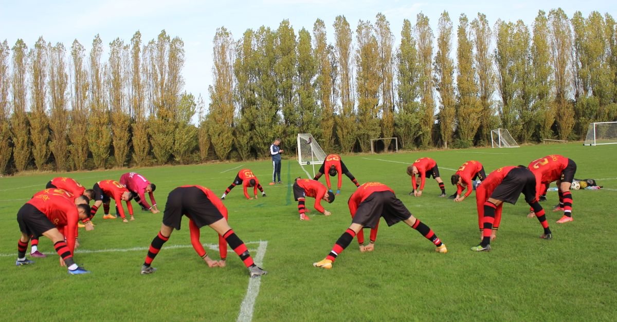 Soccer team stretching on the field before a game on a clear day, preparation for the match.