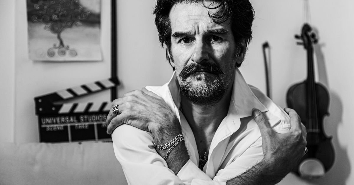 Emotionally compelling black and white portrait of a man with a violin in the background.