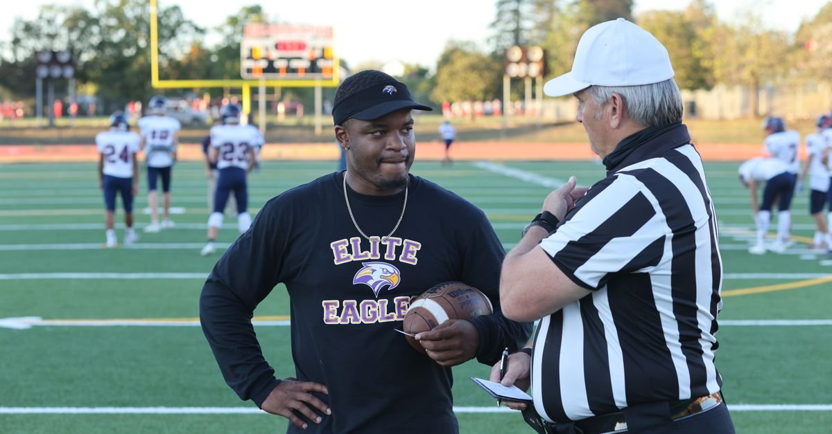 A referee and a football coach discuss the game strategy on the field.