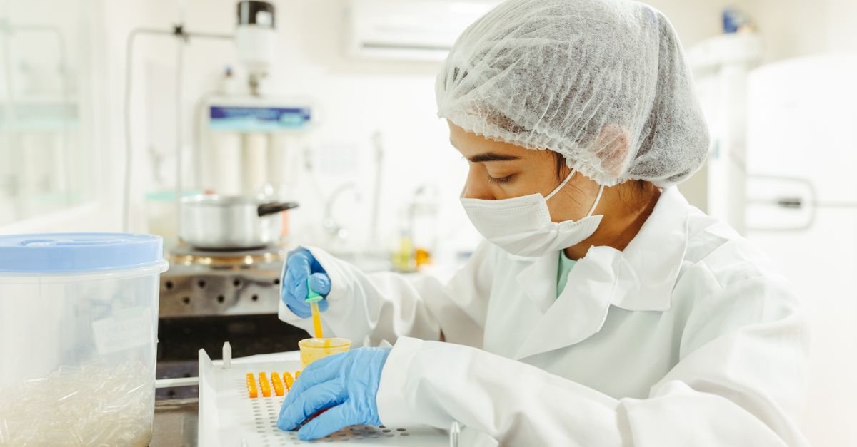 A scientist wearing protective gear performs a meticulous experiment in a laboratory setting.