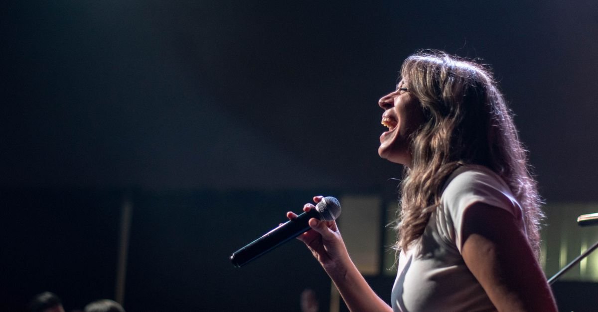 Charismatic female singer performing passionately on stage during a live concert.