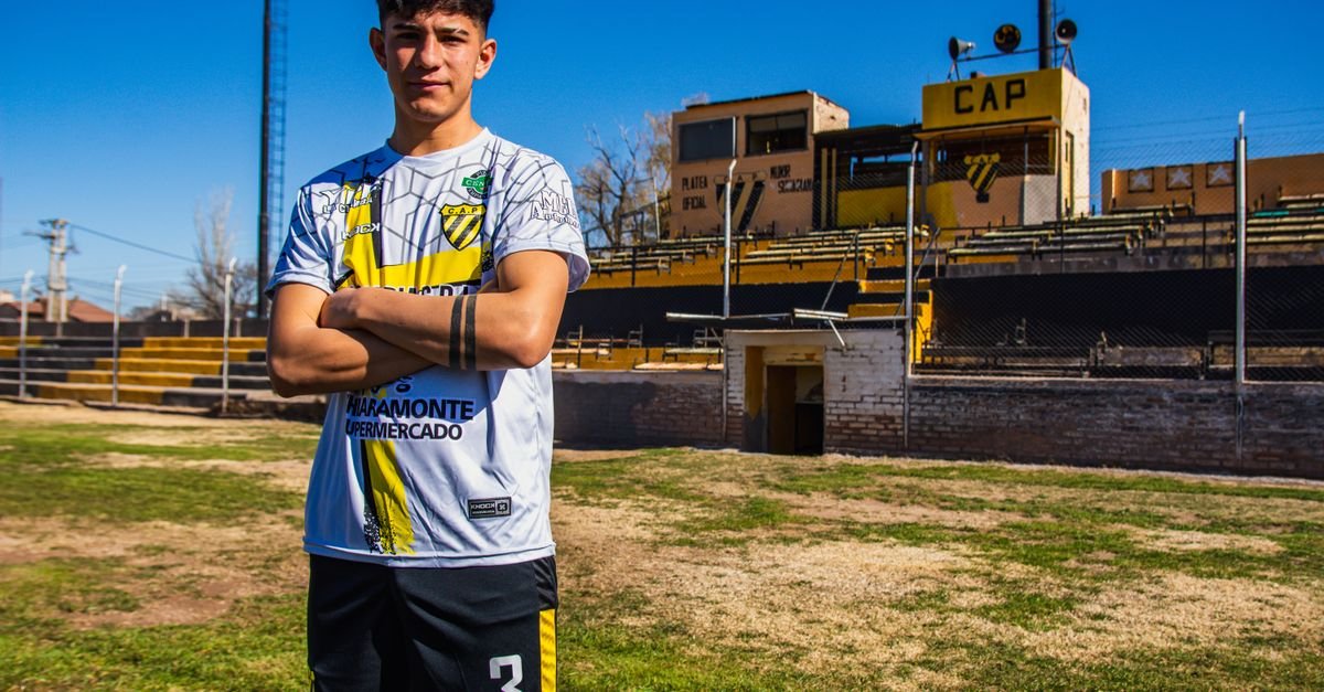 Confident young soccer player posing on the field during a bright day.