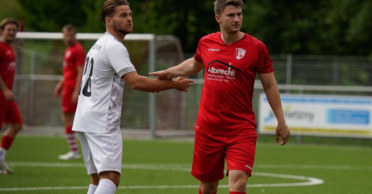 Players engage in an intense football match on a green outdoor pitch.