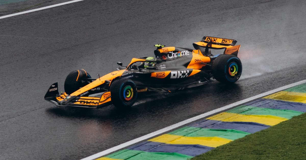 A vibrant Formula One car speeding on a wet track, showcasing dynamic motorsport action.