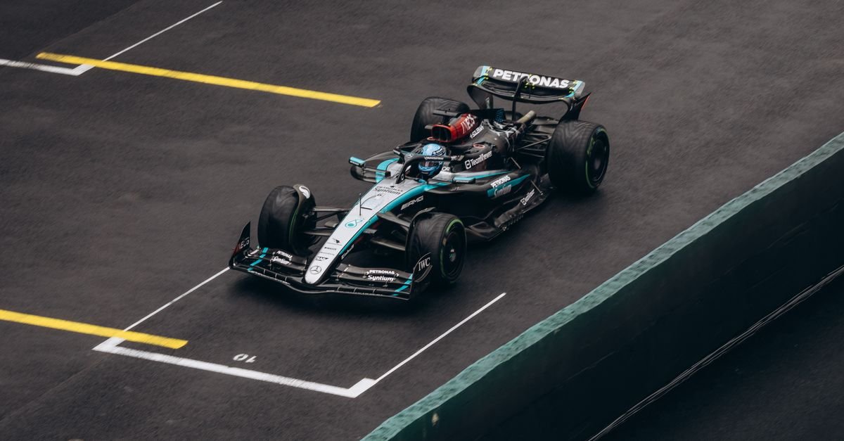 Dynamic shot of a Formula One car racing on wet asphalt, showcasing speed and precision.