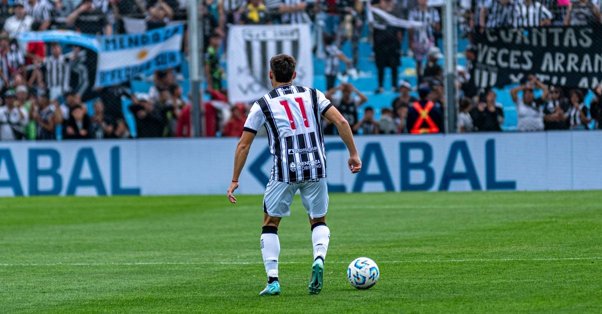 Soccer player number 11 in action on field during a match with cheering fans in the background.