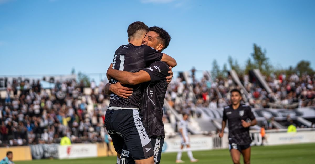 Two soccer players embracing in celebration on the field during a match.