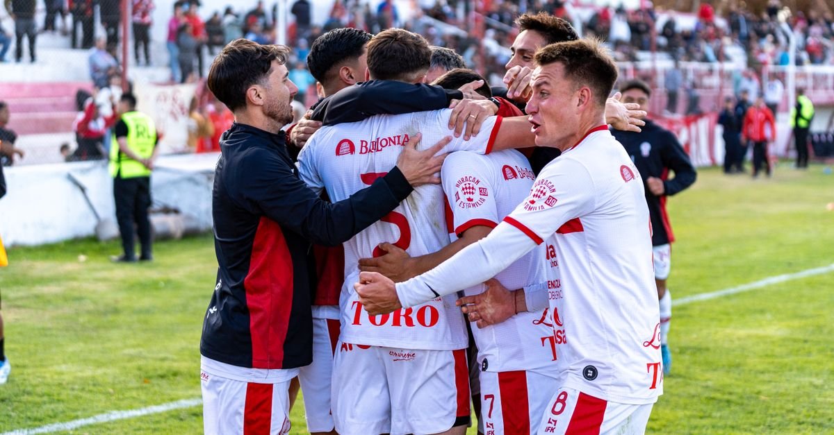Dynamic image of a soccer team celebrating a goal during an outdoor match, highlighting teamwork and excitement.