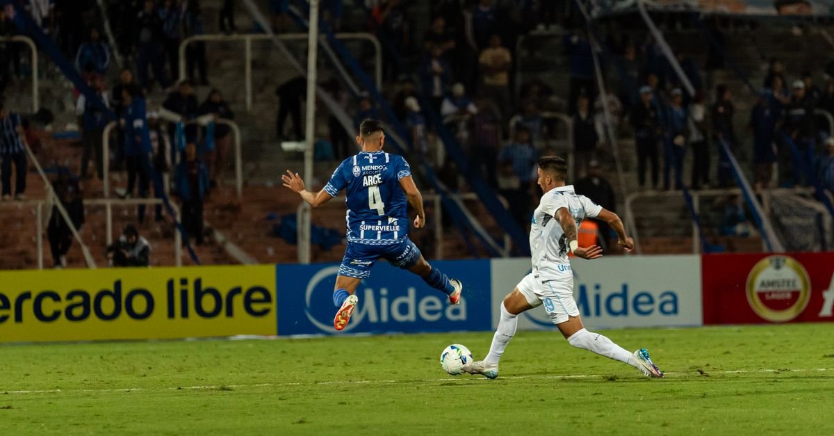 Intense football match capture with two players battling for the ball amid a cheering crowd.