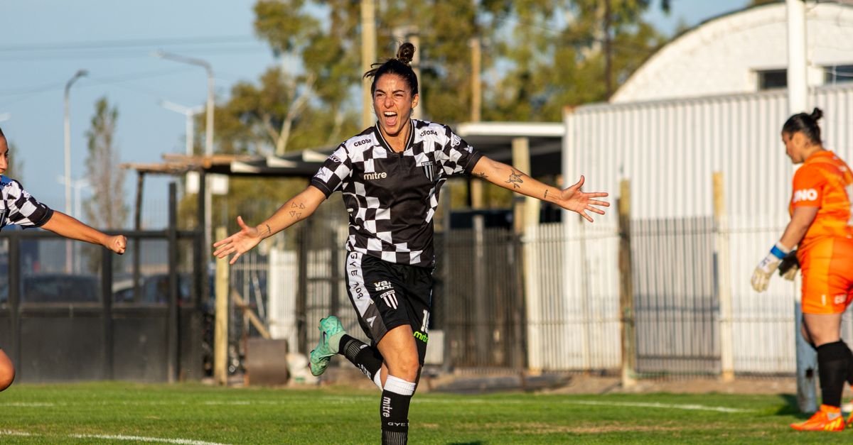 A female soccer player celebrating a goal during an outdoor match.