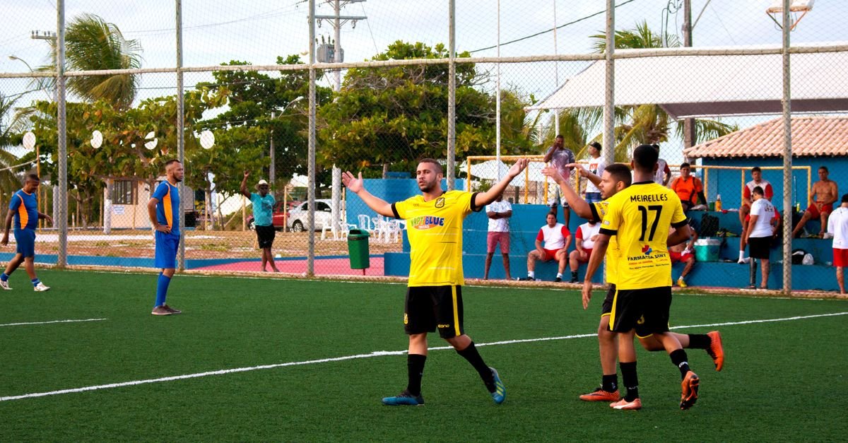 Amateur soccer team in yellow jerseys celebrates a goal during a match on an outdoor field.