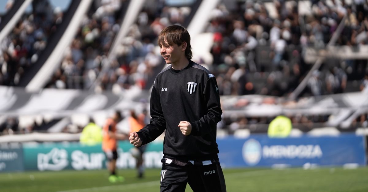 A young football player happily celebrates during a game, with a packed stadium in the background.