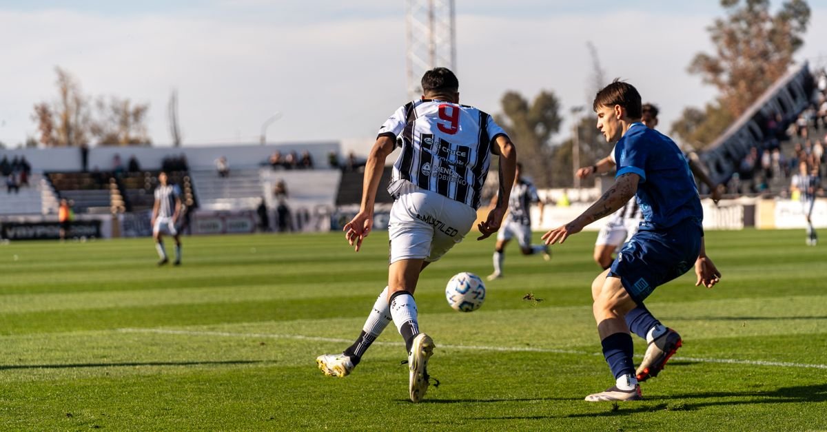 Players in action on the soccer field during an outdoor match under the bright sun.