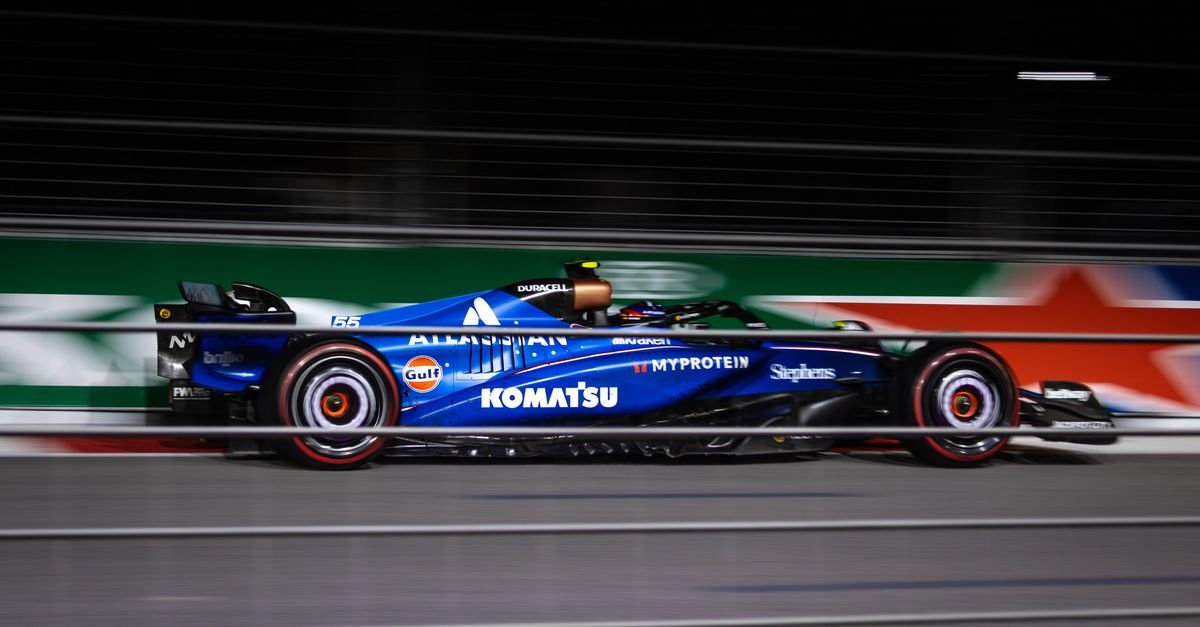 Blue Formula car speeding on track during night race.