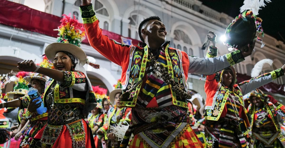 Joyful dancers in colorful traditional costumes celebrate a Bolivian carnival at night.