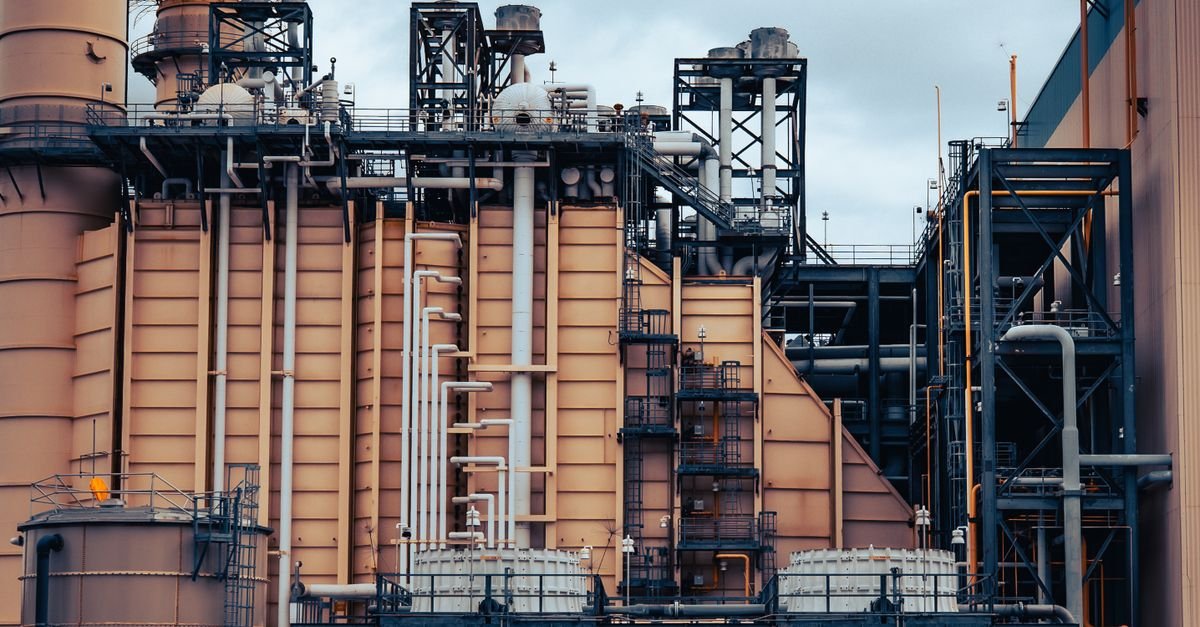 Detailed view of an industrial factory's exterior, showcasing machinery and structures under a cloudy sky.