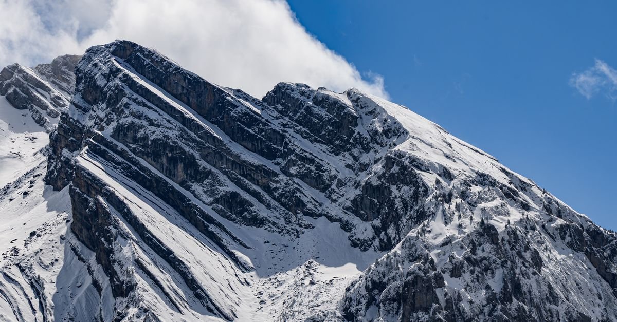 Dramatic snow-covered mountain peaks in the Swiss Alps with billowing clouds and deep blue sky.