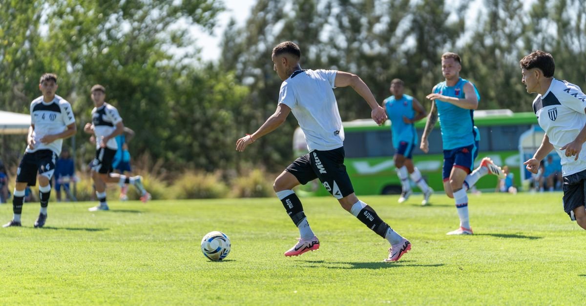 Players engaged in a competitive soccer match outdoors on a sunny day.