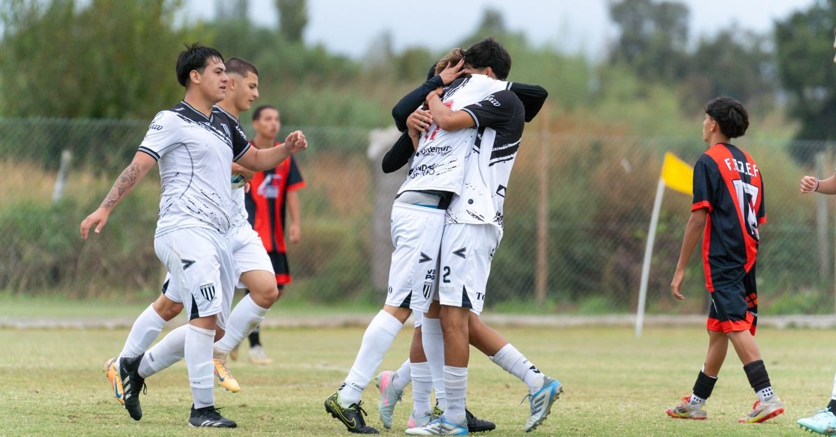 Young soccer players celebrate a goal during a match on a grassy field.