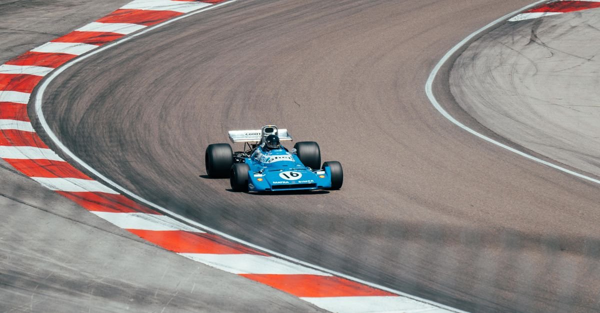 Vintage blue race car speeding on a winding track in Prenois, France.