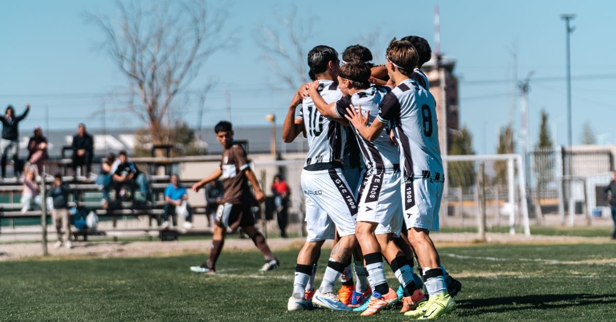 A youth soccer team in white jerseys celebrates a win on a sunny day.