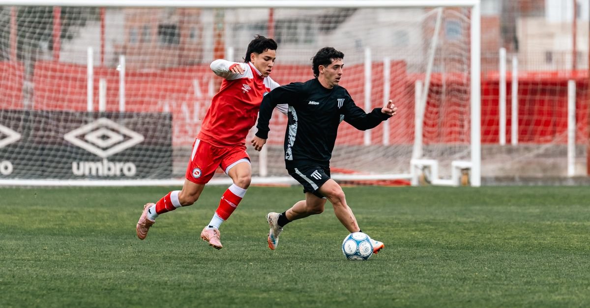 Two soccer players in action during a competitive match on a green field.