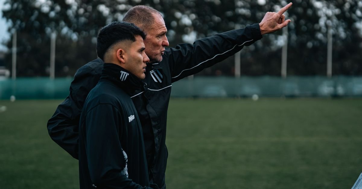 A soccer coach discusses strategy with a young player during outdoor training.
