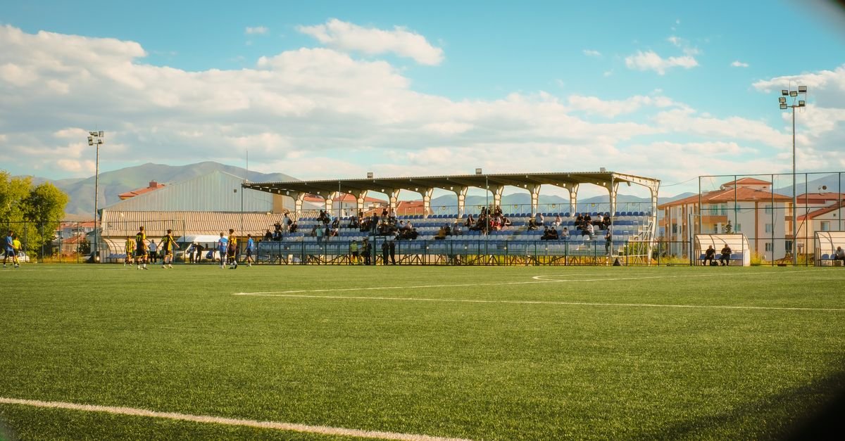 A grass soccer field with players and spectators in Malatya, Türkiye.