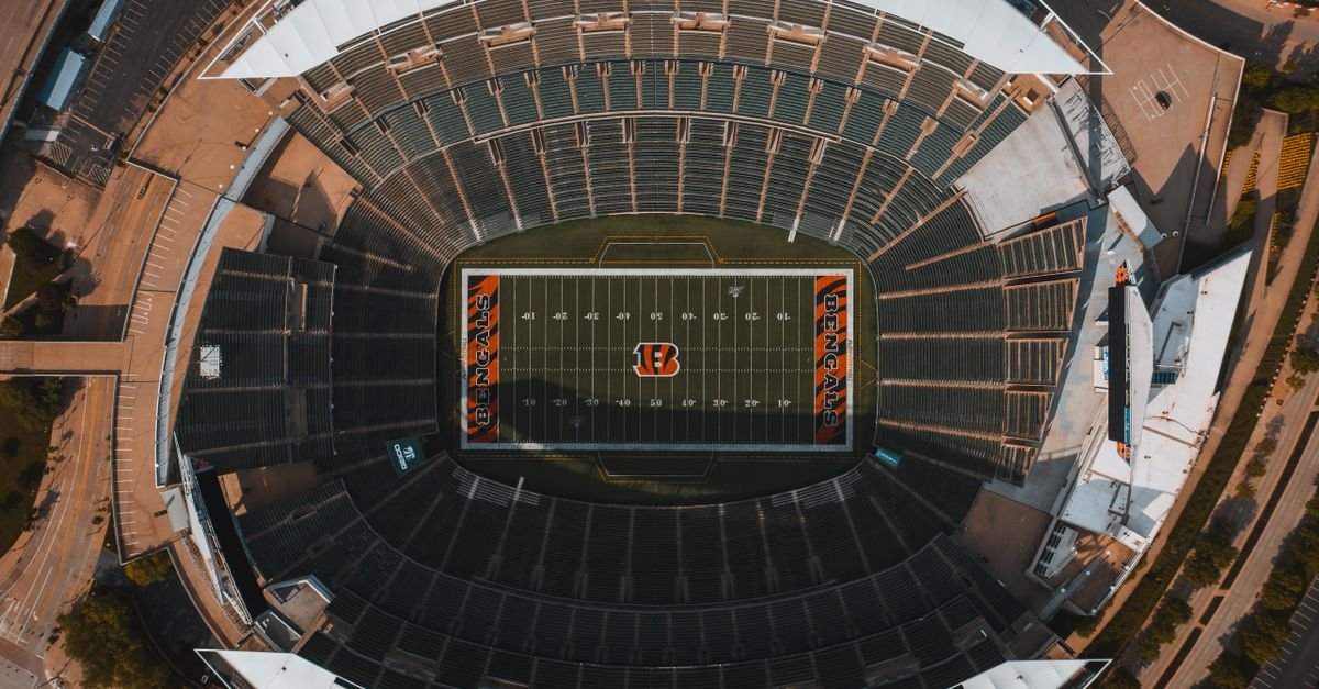 From above drone view of empty American football stadium with white lines and emblem on sunny day