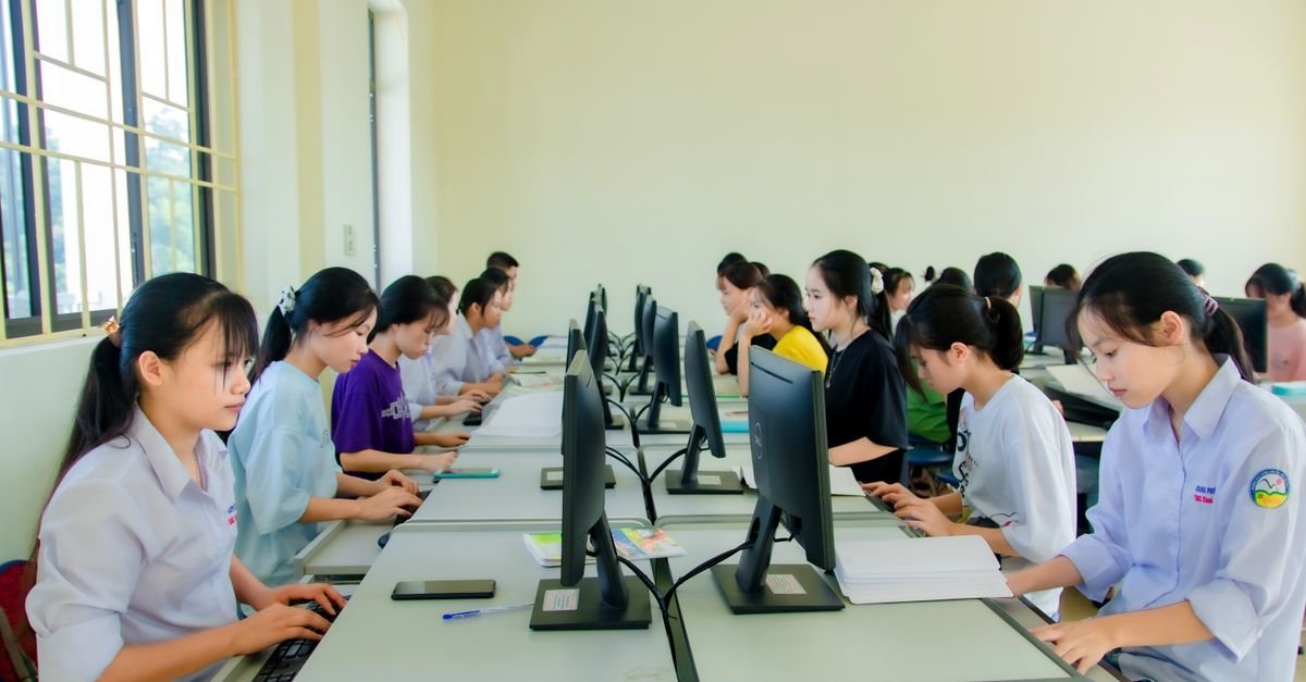 A group of students focusing on computers during a class in a university setting, working indoors.
