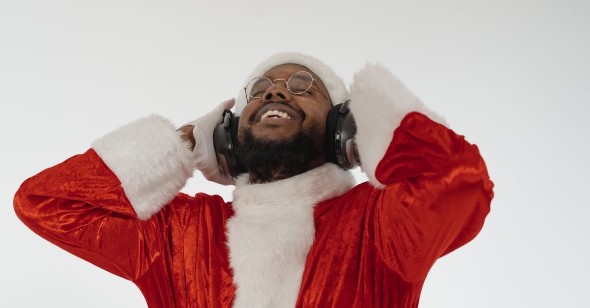 Festive Santa enjoying music, dressed in traditional red and white costume, smiling joyfully.