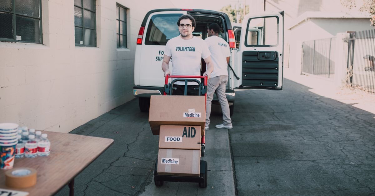 Volunteers unloading aid boxes with essential supplies like food and medicine.