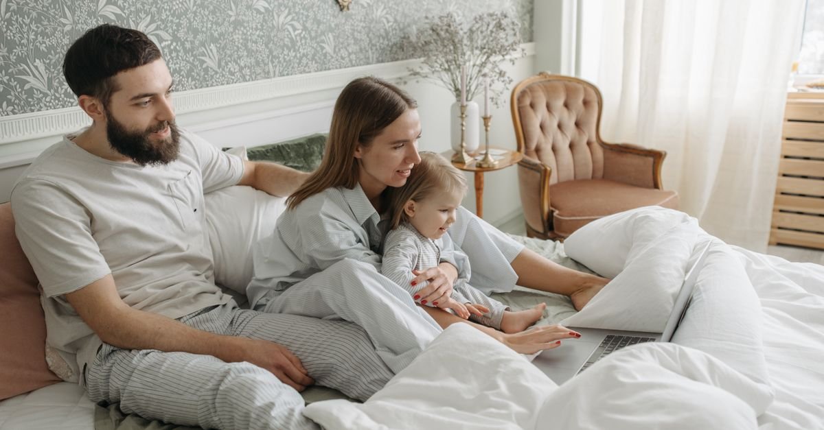 Family spending quality time together in the bedroom, watching on a laptop.