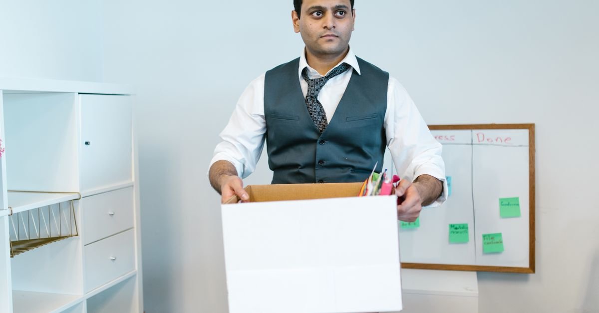 Professional man organizing office belongings in a cardboard box, preparing for transition.