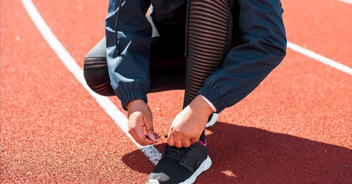 Close-up of an athlete tying sneakers on a track during the day. Perfect fit concept.