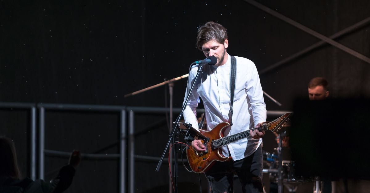 A musician passionately playing an electric guitar on stage during a live concert in Lithuania.